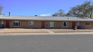 A single-story motel with a flat roof, multiple windows, and a parking lot in front. - 1Bd, King, Brkfst, Large TVs, W/D, Sleeps 4, BBQ (Page)