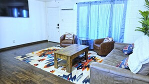 Un salon avec une table basse en bois, deux canapés en cuir marron et un tapis à motifs.