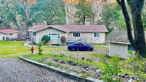 A residential area with houses, a driveway, and a blue car parked in front of one house.