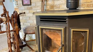 A wood-burning stove with a glass door, set against a brick wall with framed pictures.