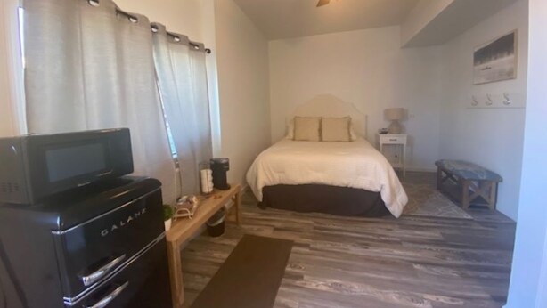 A bedroom with a bed, a ceiling fan, a microwave, and a small table. - Charming Room 7 in the St. Maries Inn (Saint Maries)