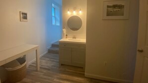 A hallway with a white vanity, a round mirror, and a framed picture on the wall. - Charming Room 7 in the St. Maries Inn (Saint Maries)