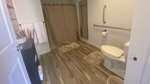 A bathroom with a shower, toilet, and a towel rack. - Charming Room 7 in the St. Maries Inn (Saint Maries)