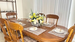 Ein Holztisch mit vier Stühlen, eine Blumenvase und ein dekoratives Regal mit Gegenständen.