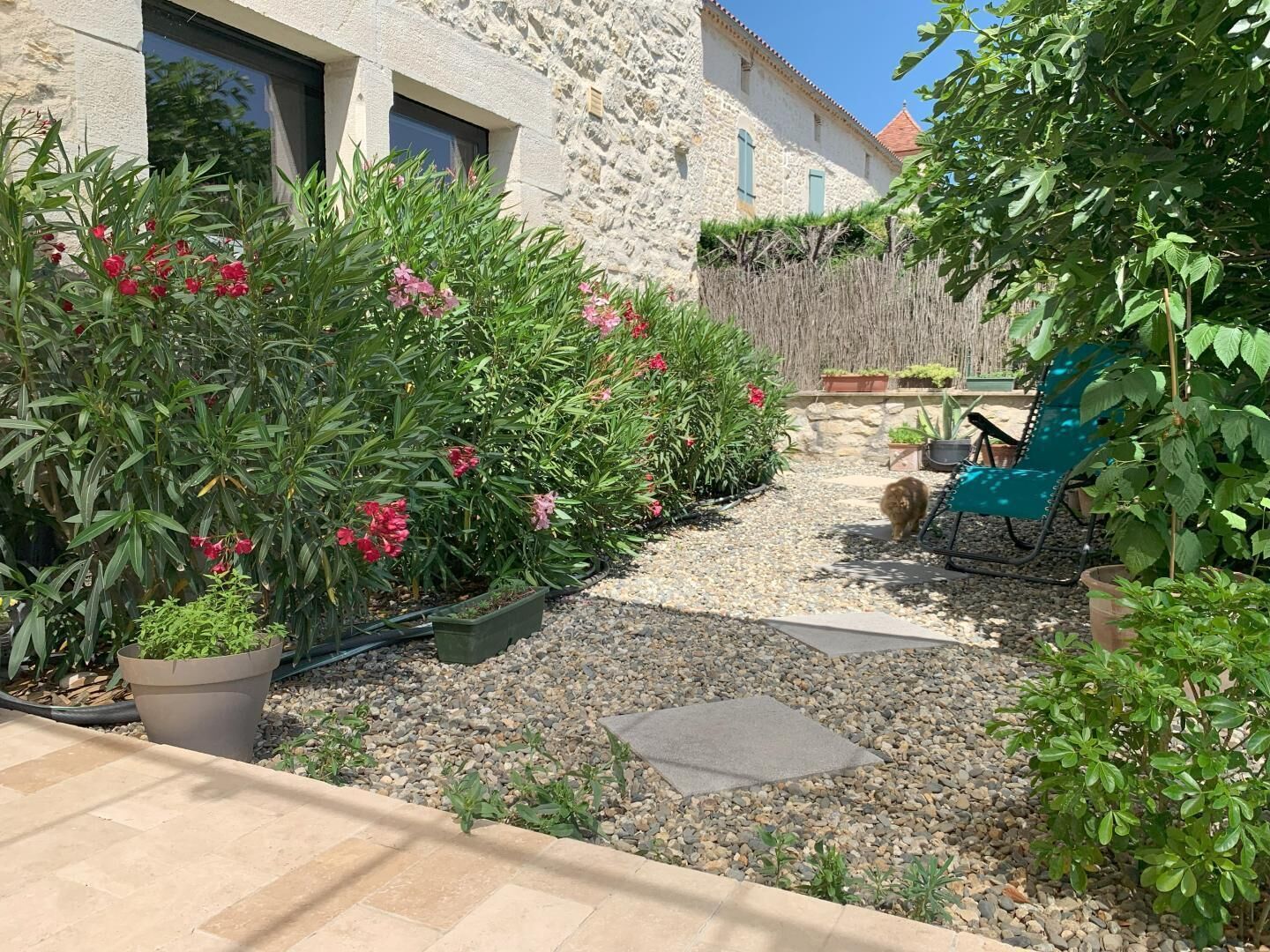 A stone building with a gravel pathway leading to a seating area with a blue chair.