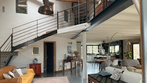 A spacious living area with a staircase, a sofa, a coffee table, and a dining area.