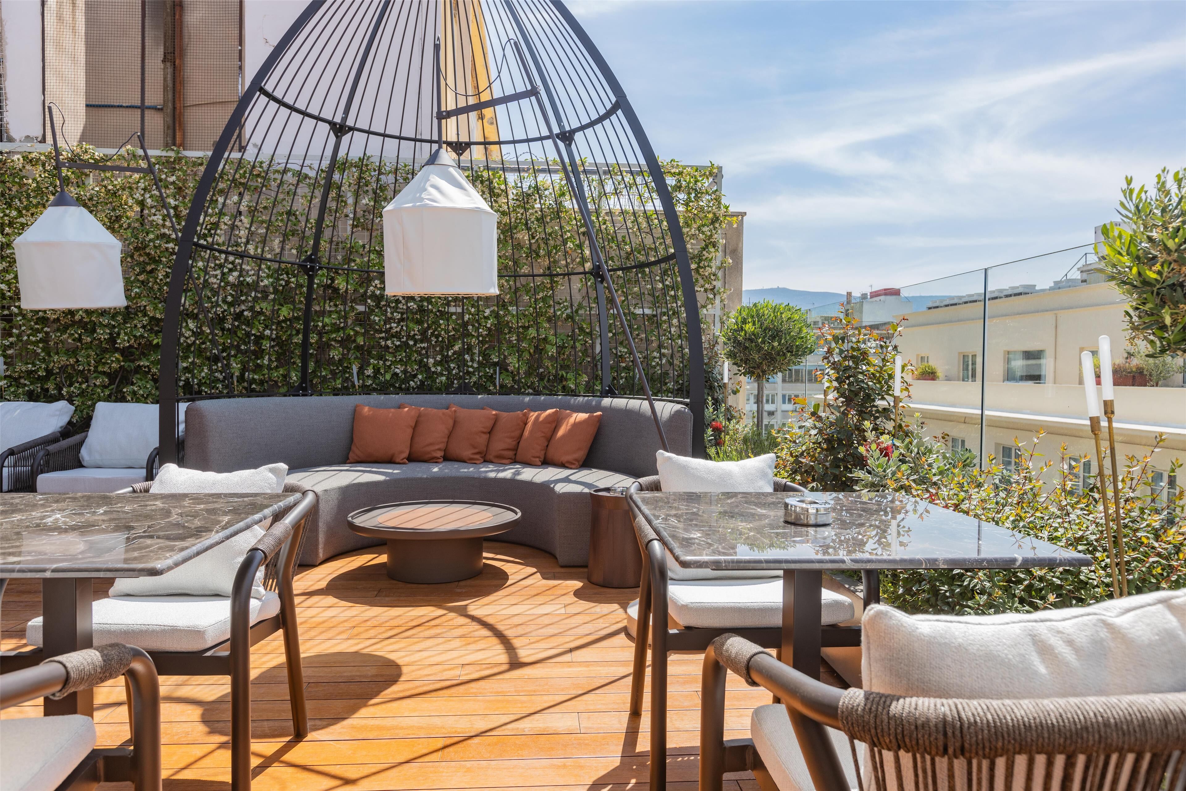An outdoor seating area with a round table, cushioned seating, and pendant lights.