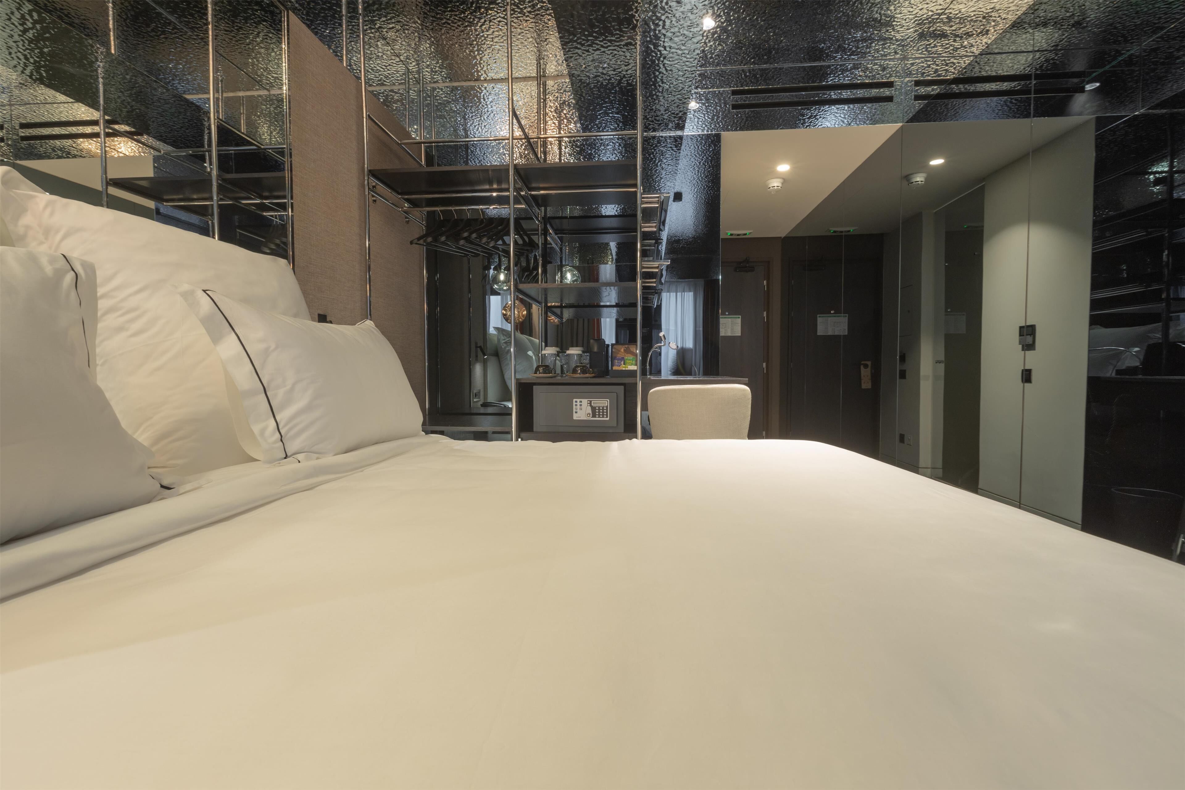 A modern hotel room with a large bed, a desk, and a view of the interior.