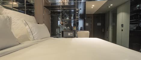 A modern hotel room with a large bed, a desk, and a view of the interior.