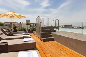 A rooftop terrace with sun loungers, a pool, and a view of the city. - Adia Aluma Athens, Curio Collection By Hilton (Athens)