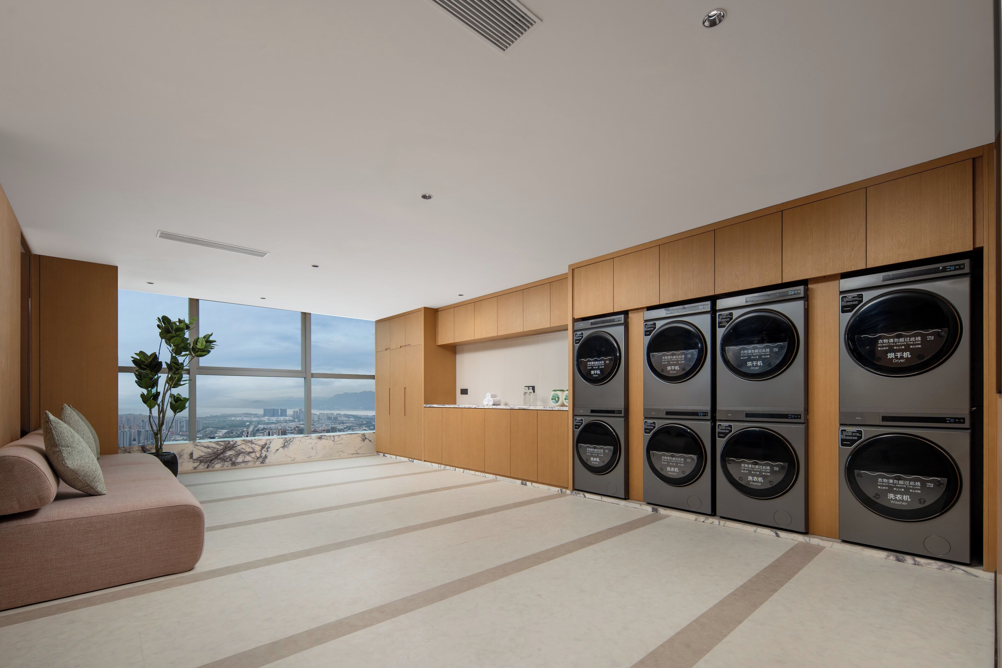 A modern kitchen with built-in appliances, a seating area with a view, and a large window overlooking a cityscape.