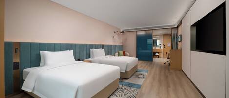 A modern hotel room with two beds, a desk, and a TV.