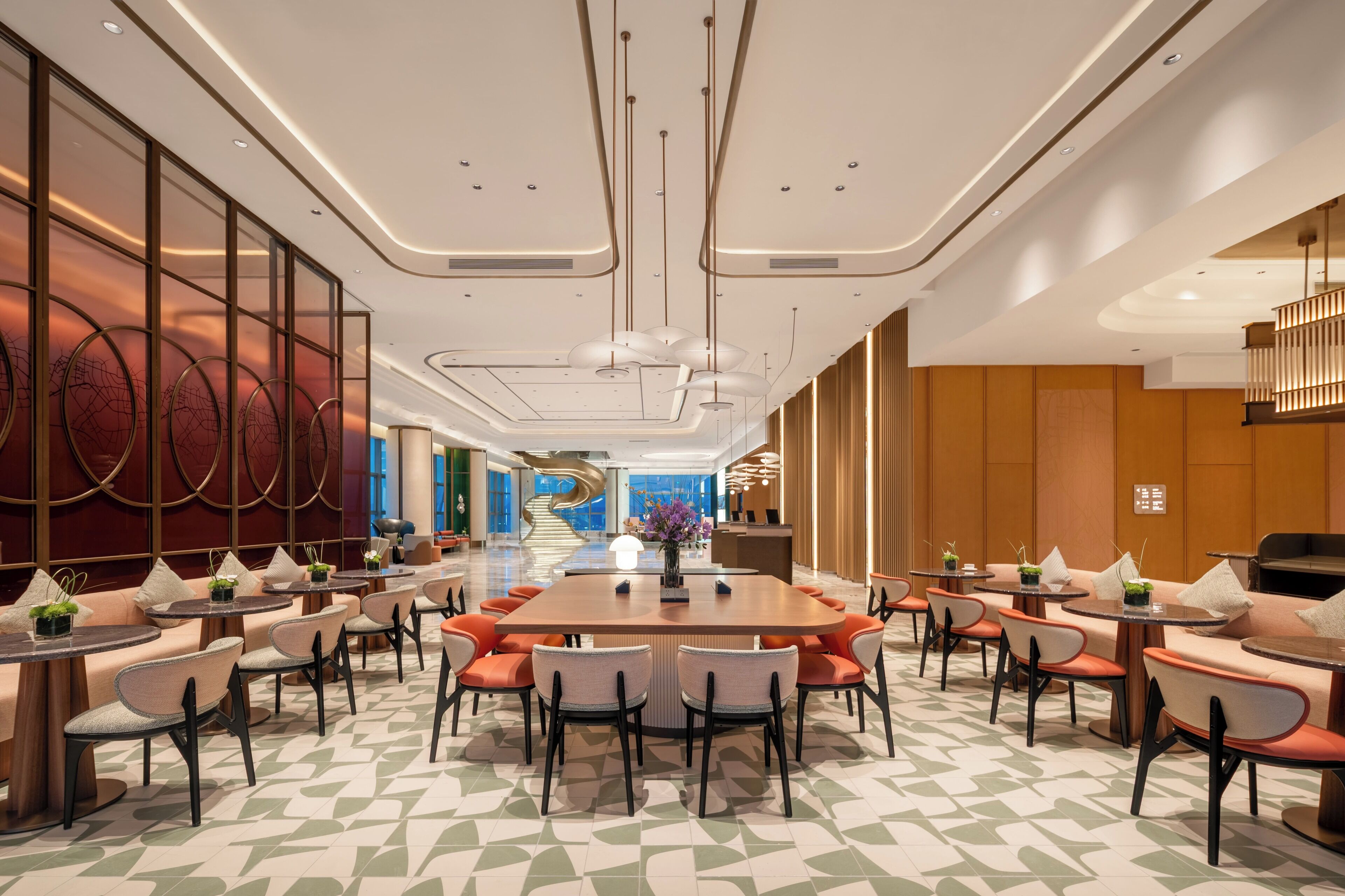 A spacious hotel lobby with a central dining area, multiple seating options, and a modern design.