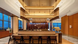 A modern bar area with a central island, seating, and a unique ceiling design.