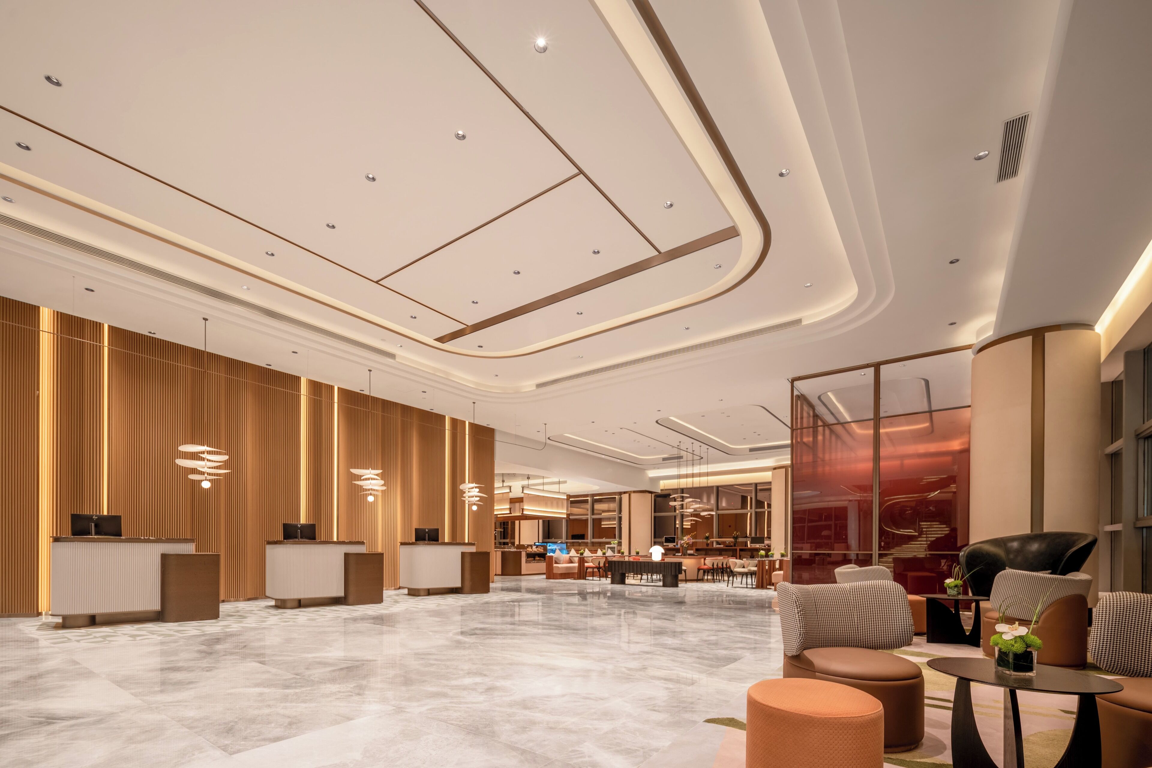 A spacious lobby with a reception desk, seating area, and modern lighting.
