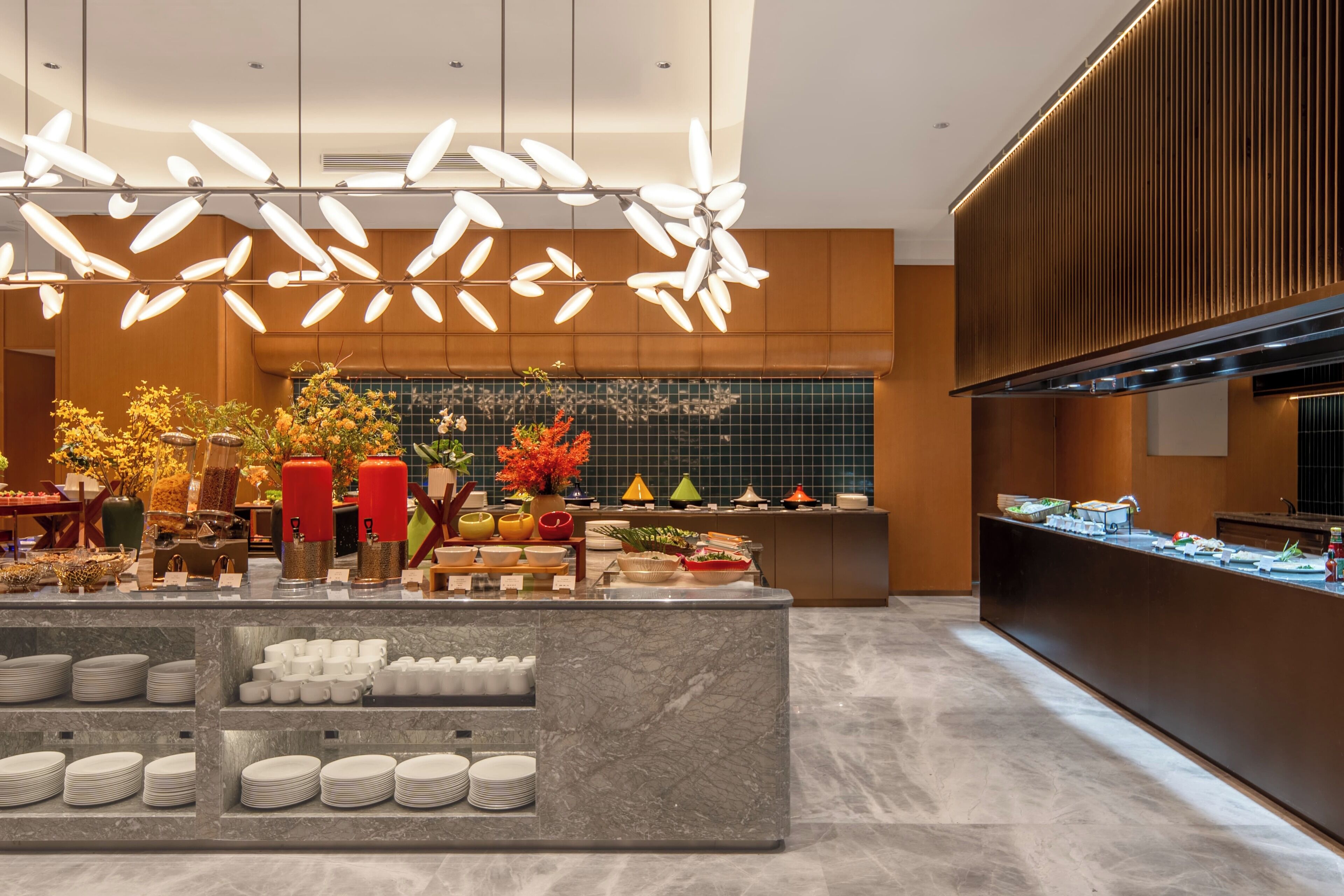 A modern kitchen with a marble island, a variety of dishes, and a decorative light fixture.