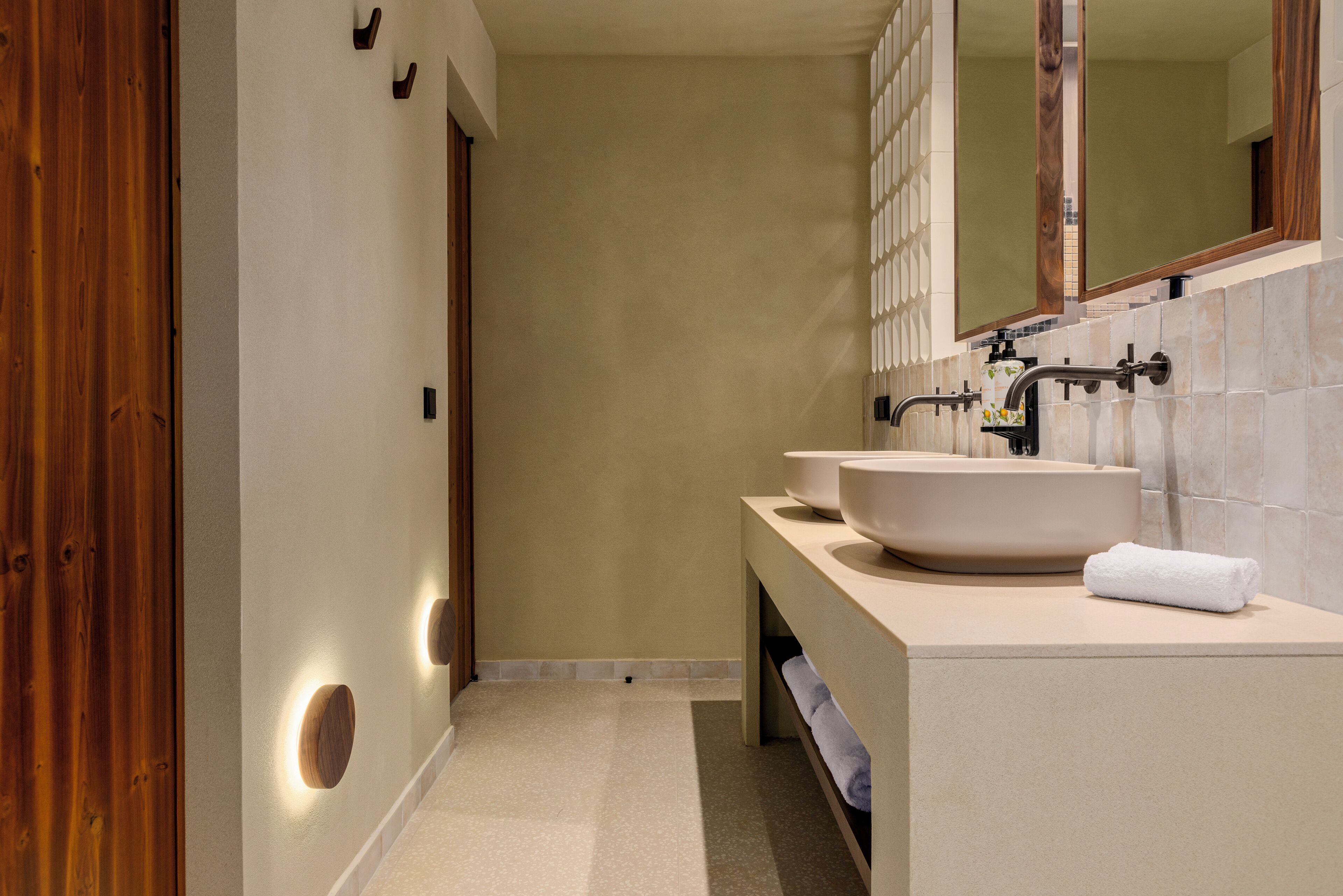 Une salle de bain moderne avec deux lavabos, un grand miroir et une porte en bois.