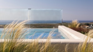 Una piscina con vista al océano, rodeada de hierba alta.