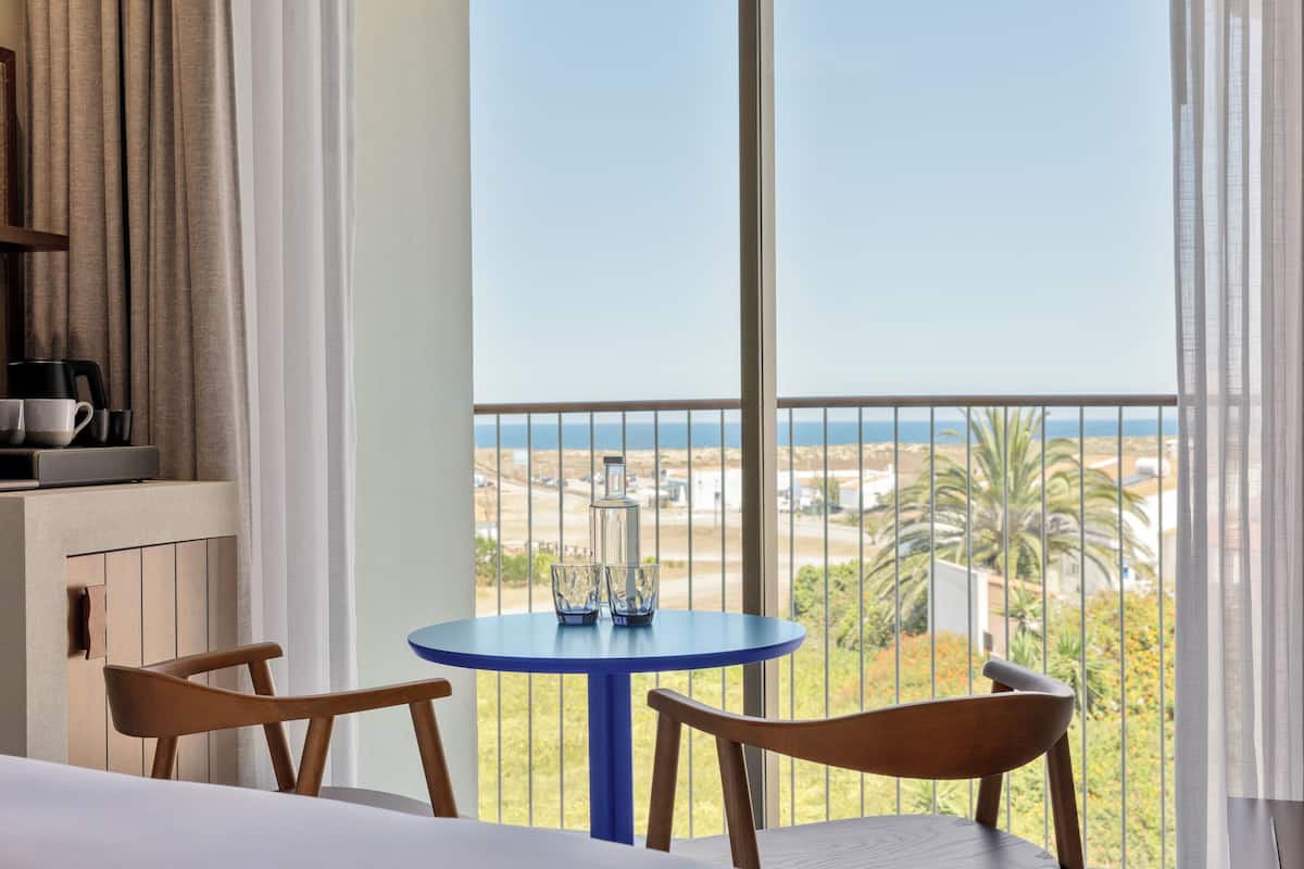 Un balcon avec une table et des chaises, donnant sur un paysage côtier.