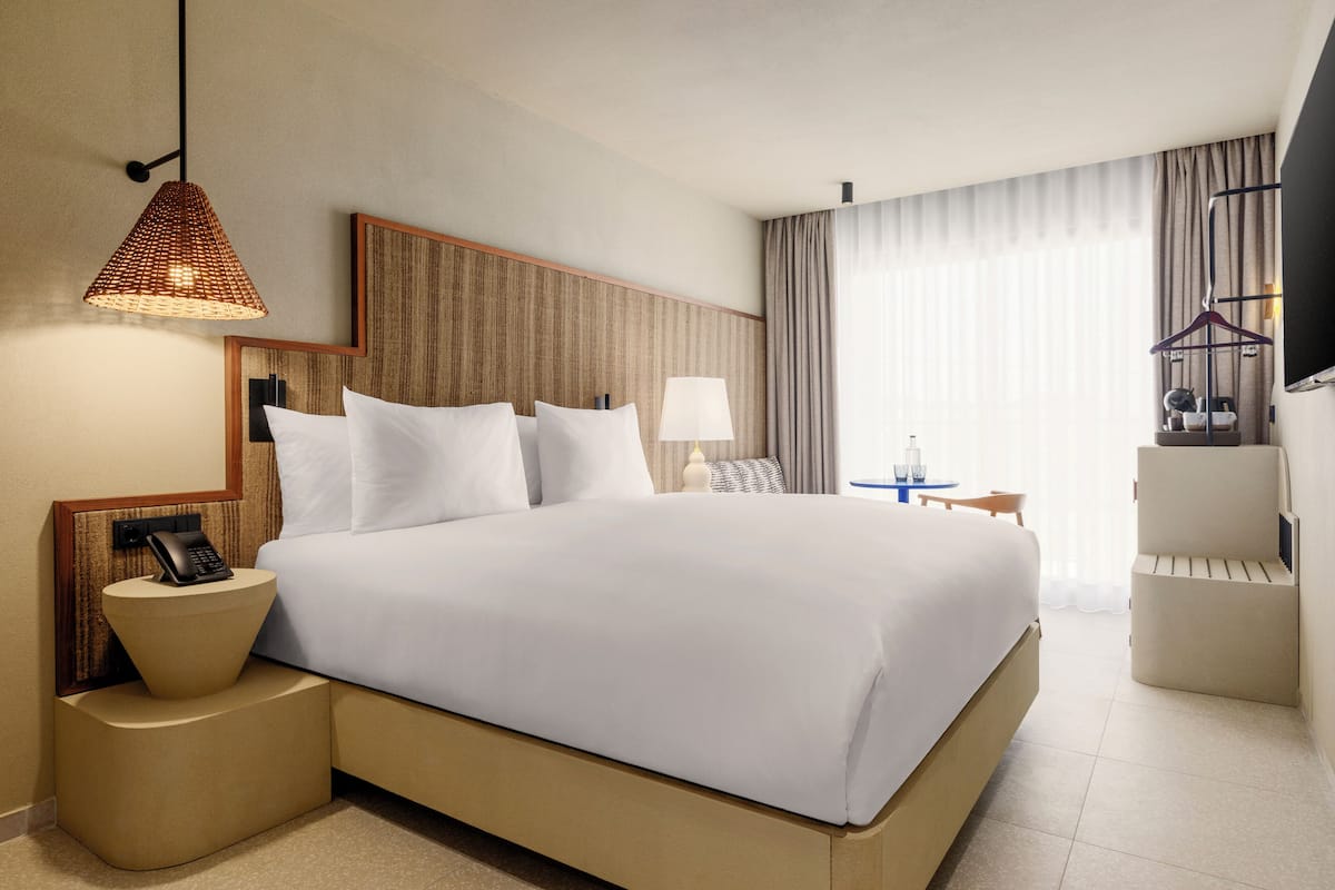 Une chambre d’hôtel avec un grand lit, des tables de chevet, une lampe, une télévision et une chaise.