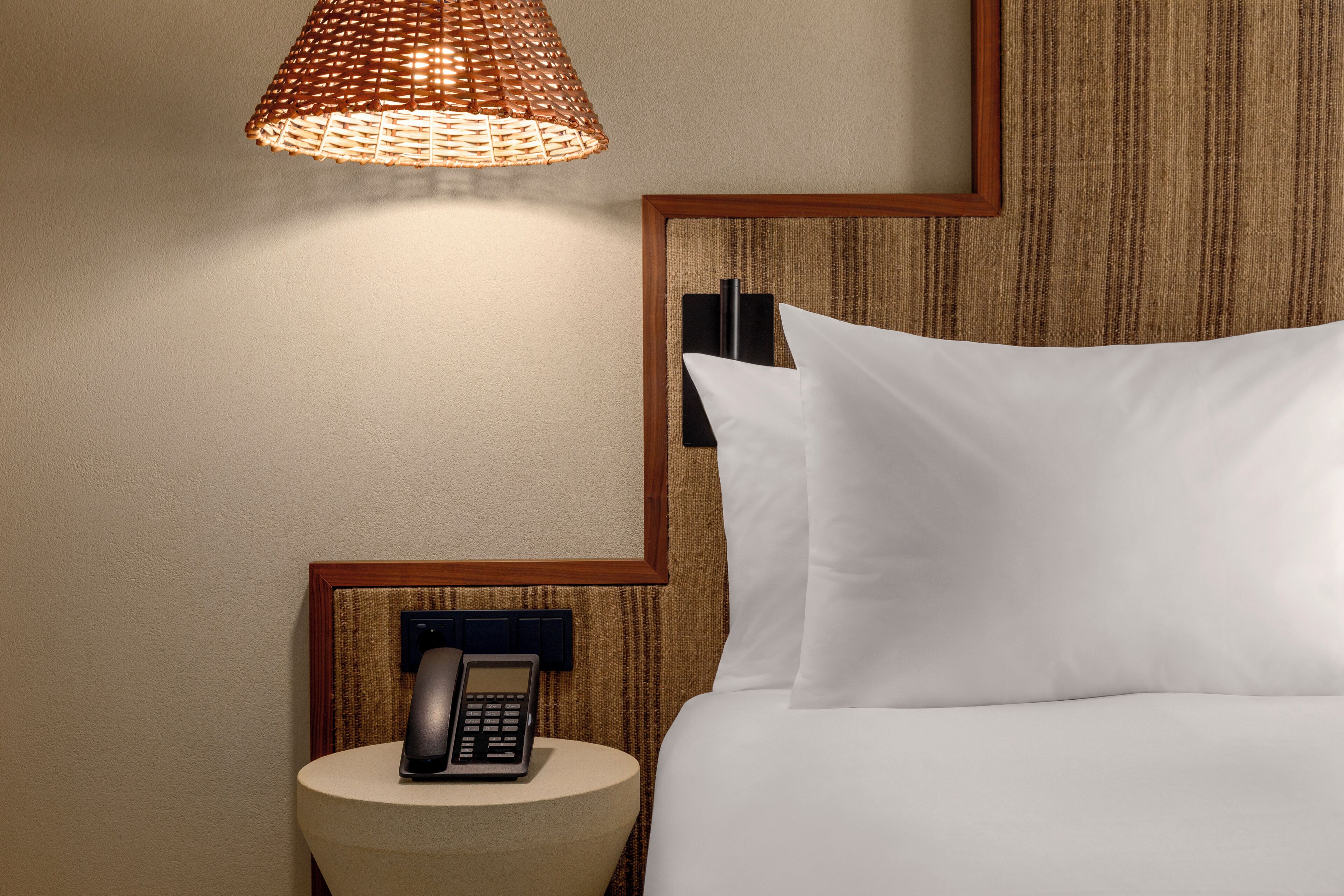 Una habitación de hotel impecable con una cama, una mesita de noche con lámpara y un teléfono.