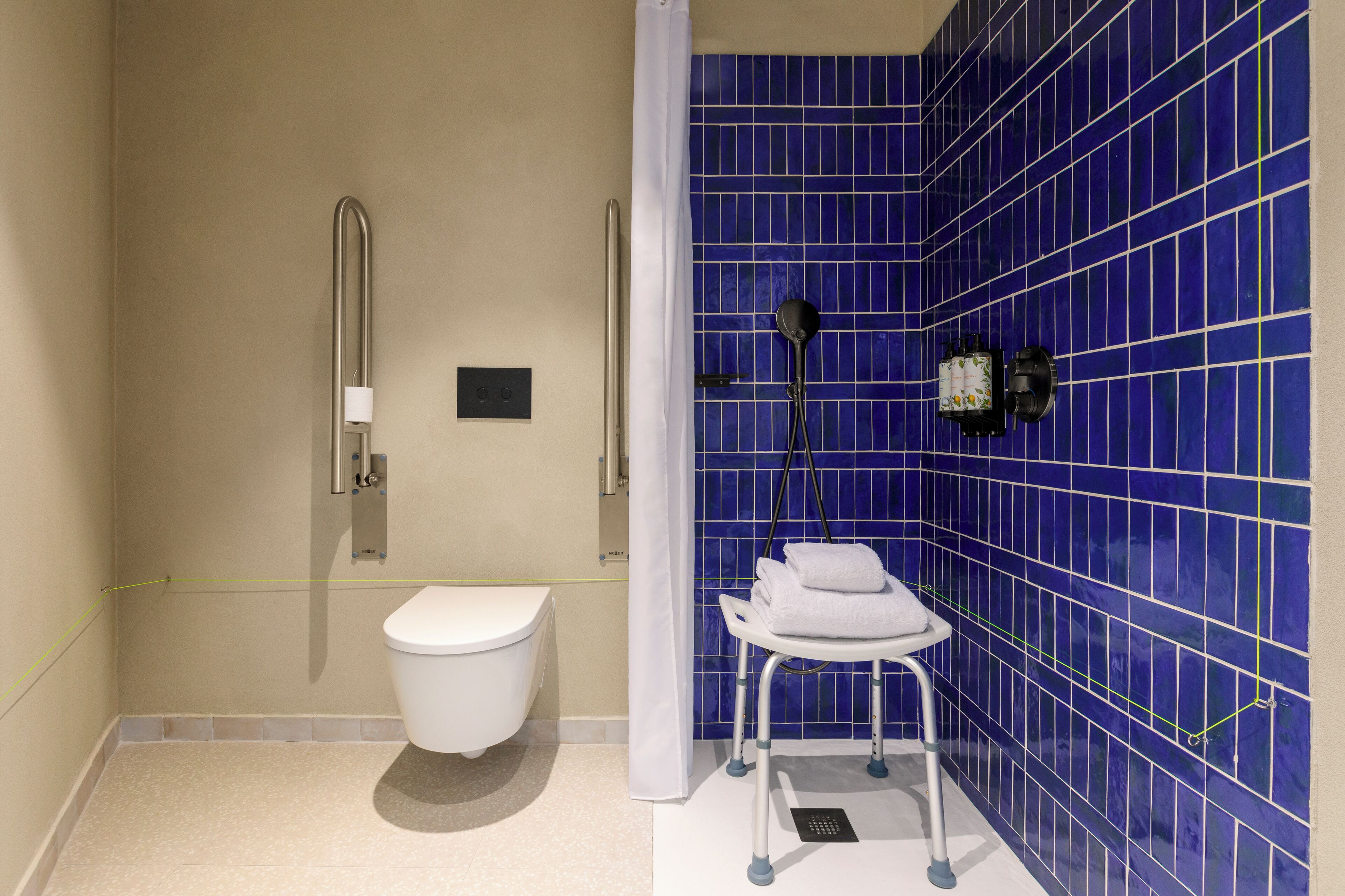 A bathroom with a white toilet, a shower with a white curtain, and a blue tiled wall.