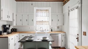 Una cucina con mobili bianchi, un piano di lavoro in legno, un lavandino e una lavastoviglie.