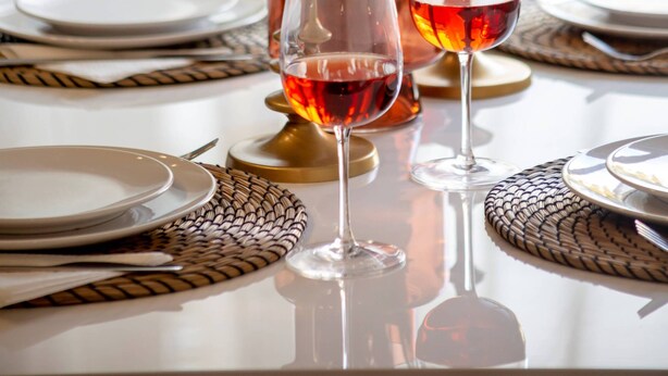 Una mesa dispuesta con platos, vasos y velas, con un jarrón de flores al fondo.