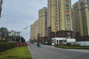 A street with high-rise residential buildings, a small white building, and a clear sky. - Jinshatan Family Hostel (Qingdao)