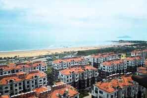 A coastal residential area with apartment buildings, a beach, and a distant mountain. - Jinshatan Family Hostel (Qingdao)
