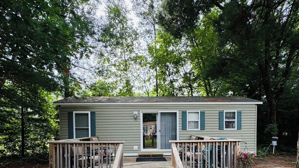 A single-story cabin with a front porch, a small deck, and a grill outside. - Rental Cabin #403 w/ Queen bed (Wisconsin Dells)