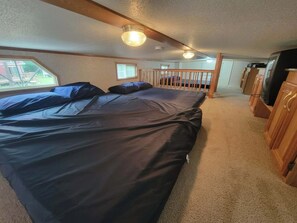 Ein Schlafzimmer mit Bett, Fenster, Holzbalken und Fernseher.