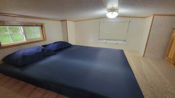A bedroom with a bed, a window, and a ceiling fan.