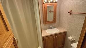 Ein Badezimmer mit Dusche, Waschbecken, Toilette und einem beleuchteten Spiegel.
