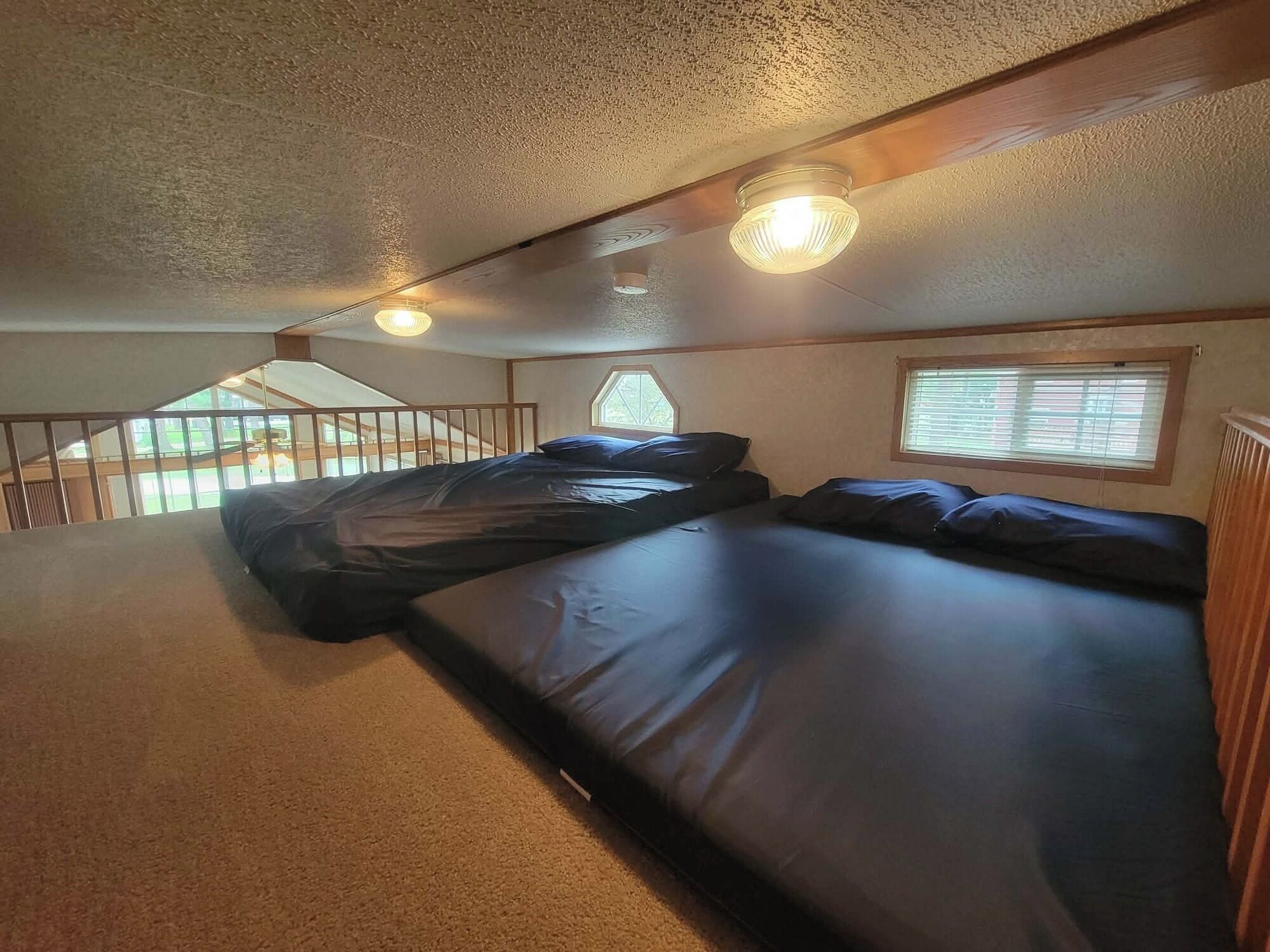A bedroom with a large bed, a window with blinds, and a ceiling fan.