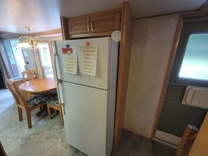 Una cocina compacta con refrigerador, armarios de madera, una mesa de comedor con sillas y un ventanal.