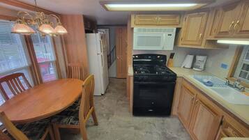 A compact kitchen with a dining table, chairs, a stove, a microwave, and wooden cabinets.