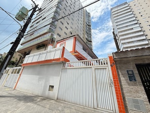 Un edificio de varios pisos con entrada porticada, fachada de azulejos y una ventana visible.