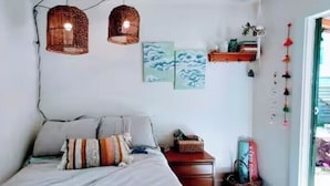 Un dormitorio con una cama, dos lámparas colgantes, un aparador y decoración en la pared.