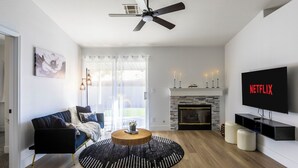 A modern living room with a sofa, a round coffee table, a fireplace, a TV, and a ceiling fan.