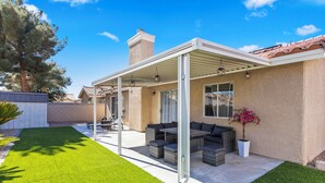 A covered patio area with outdoor furniture, a potted plant, and a view of the backyard.