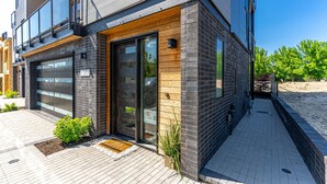 A modern building with a garage door, wooden accents, and a paved entrance area. - Millpointe Studio 1.0 - Where Luxury Meets Location -Steps to Concerts, Old Mill (Bend)