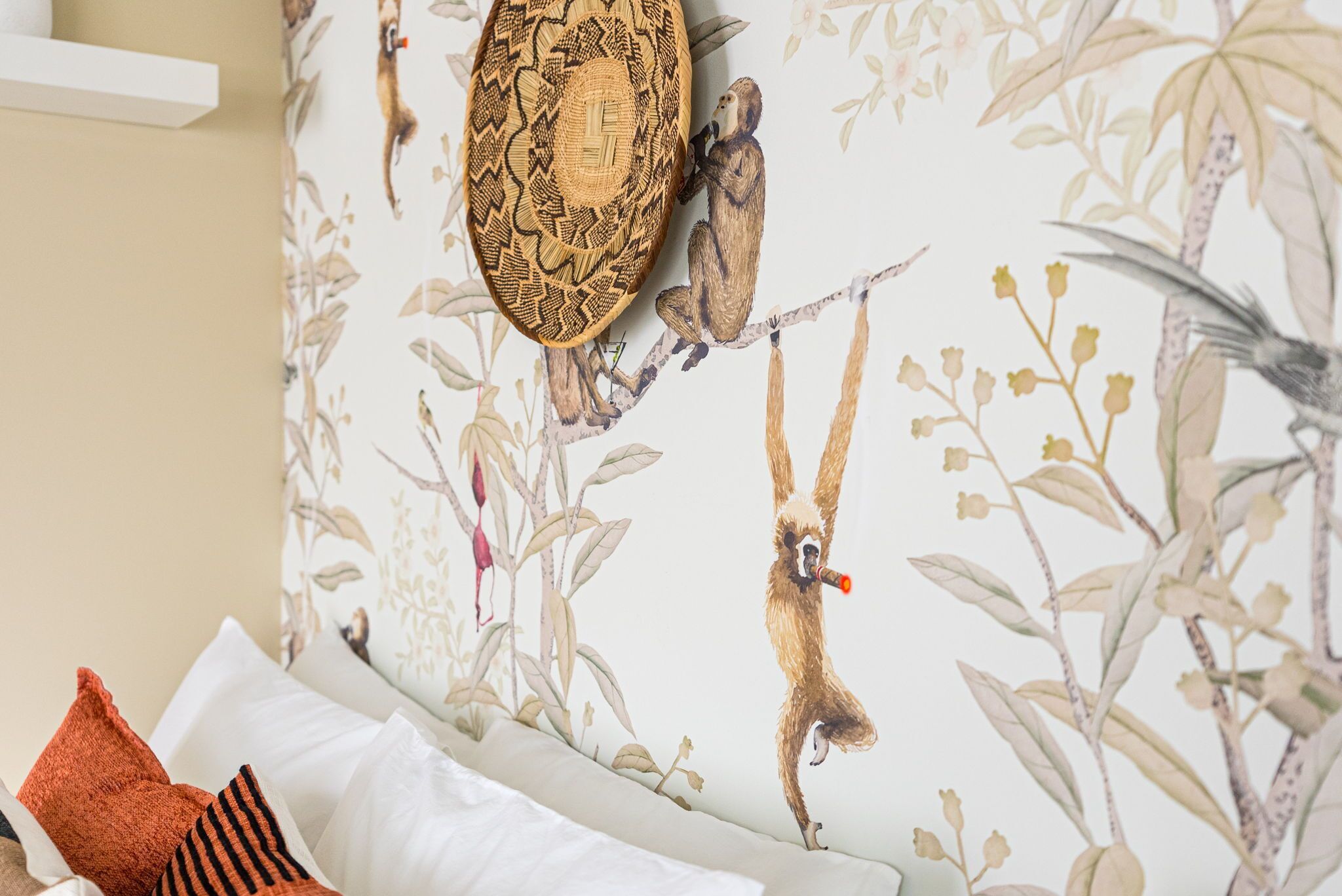 A room with a bed, pillows, and a wall with a nature-themed mural.