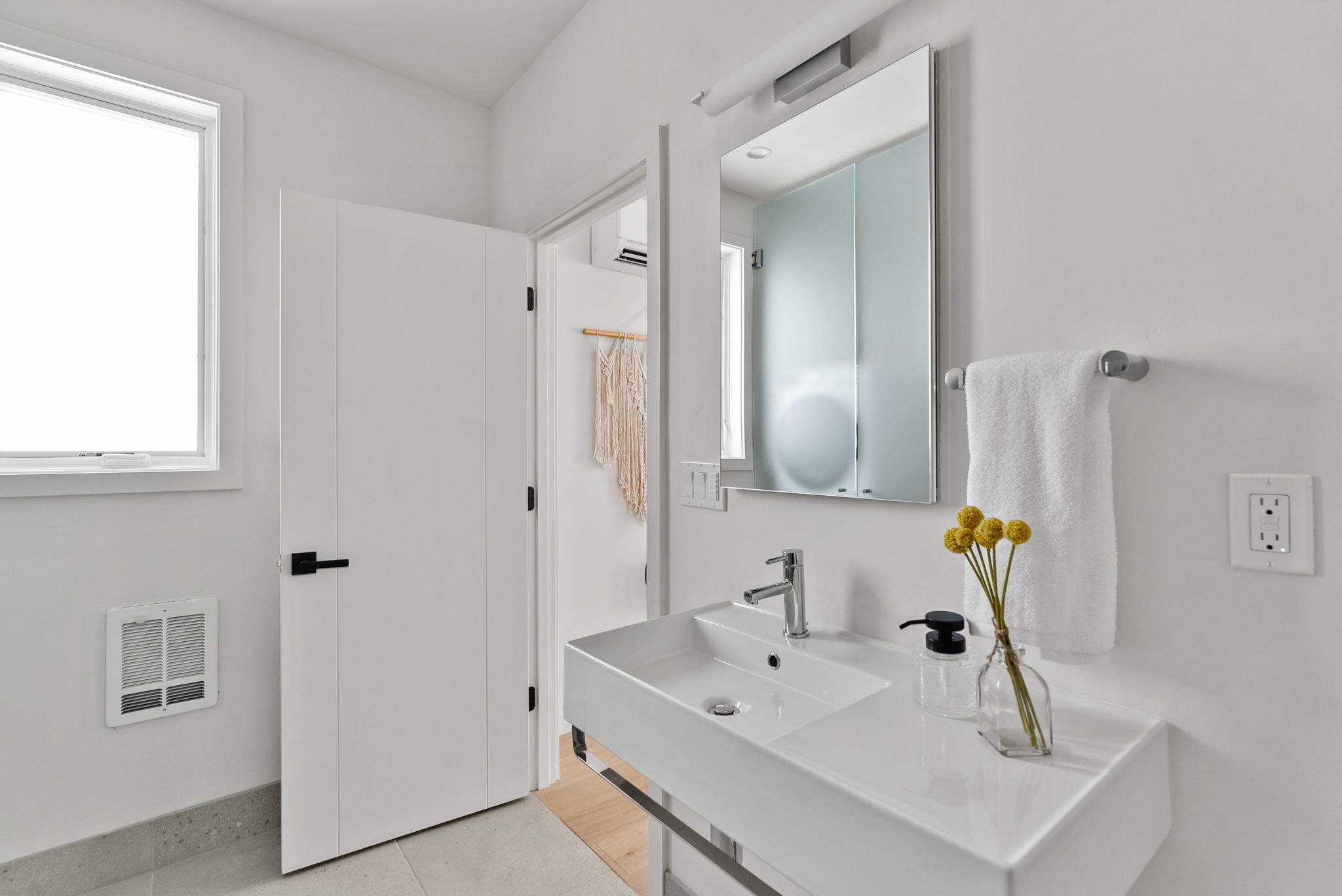A modern bathroom with a white sink, mirror, and towel rack.