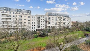 Ein modernes Apartmenthaus mit mehreren Balkonen und einer Grünanlage davor.