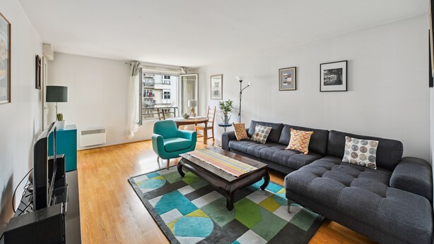 Ein modernes Wohnzimmer mit einer Couch, einem Couchtisch und einem Türkis-farbenen Sessel.