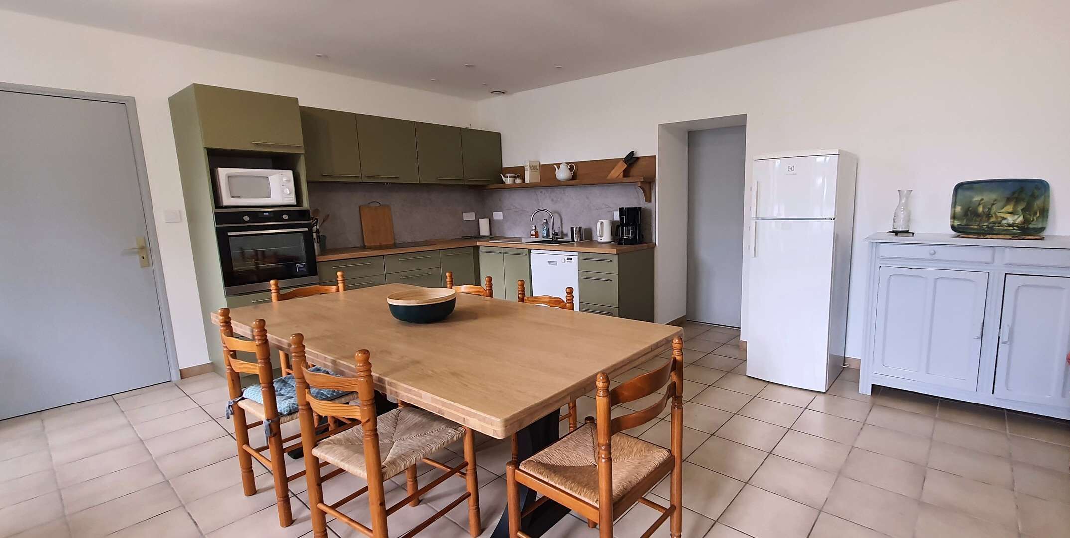 Una cocina compacta con una mesa de comedor, sillas, microondas, refrigerador y un lavabo.