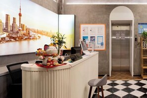 A hotel reception desk with a cityscape painting, a plant, and a digital screen. - Boke Inn (Shanghai Loushanguan Road Subway Station Branch) (Shanghai)