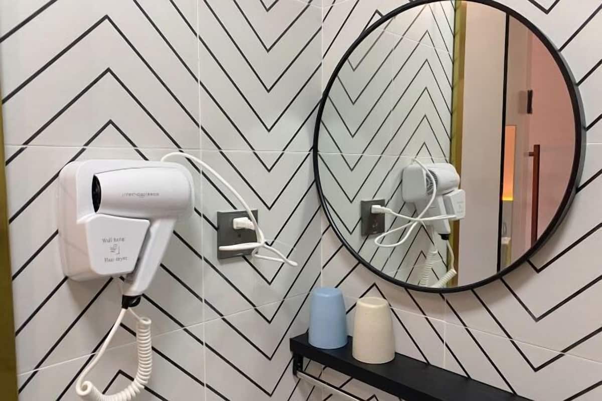A modern bathroom with a zigzag patterned wall, a hairdryer, and a mirror.
