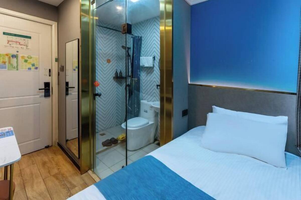 A hotel room with a bed, a shower, and a toilet.